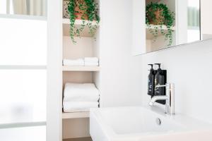 une salle de bain avec un lavabo, un miroir et des serviettes dans l'établissement Nishi Apartments Eco Living by Ovolo, à Canberra