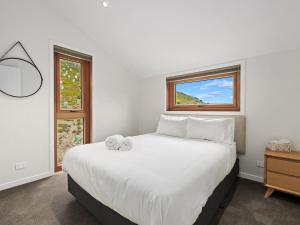 a bedroom with a large white bed with a window at The Loft at Sicilian in Queenstown