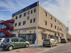 a building with two cars parked in front of it at Hotel M5 Valencia Aeropuerto in Manises