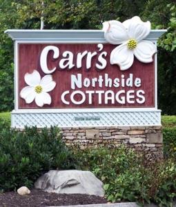 Carr's Northside Hotel and Cottages في غاتلينبرغ: وجود علامة على كوخ من الجهة الشمالية مع الزهور عليها