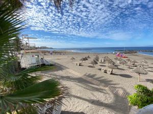 una playa con sillas y sombrillas y el océano en Paradero II, en Playa de las Américas