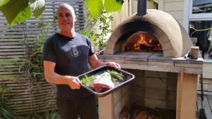 a man holding a tray of food in front of an oven at Endless Summer Lodge in Ahipara