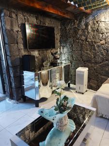 a living room with a tv on a stone wall at ALOELUXVILLA COM " I " , for couples! Design by the local artist Salvado r in Conil