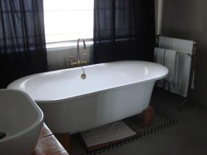 a white bath tub in a bathroom with a window at Die Waenhuis Guest House in George