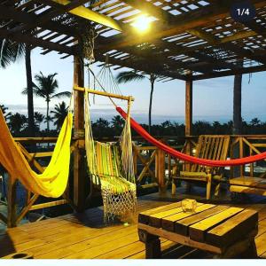 a hammock on a deck with a table and a bench at Hostel Eco Punta Cana in Punta Cana