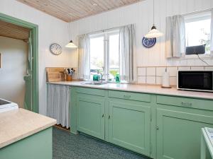 a kitchen with green cabinets and a sink at 5 person holiday home in V ggerl se in Marielyst
