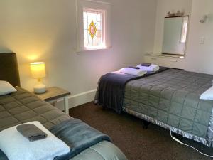 1 dormitorio con 2 camas y ventana en Beach Lodge Motels, en Dunedin