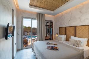 een slaapkamer met een bed, een televisie en een balkon bij Oasis Hotel Prasonisi in Prasonisi