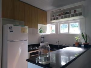 a kitchen with a white refrigerator and a jar of water on a counter at Casa Refúgio Praia Brava in Itajaí +1 photo