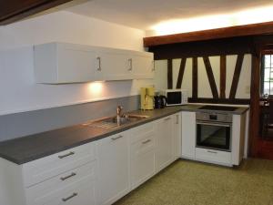 a kitchen with white cabinets and a sink at Vintage Farmhouse with Garden Roofed Terrace BBQ in Gouvy