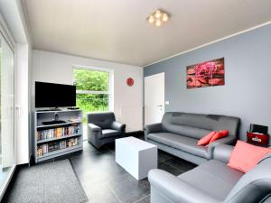 een woonkamer met een bank en een tv bij Luxurious Home with Sauna in Somme-Leuze