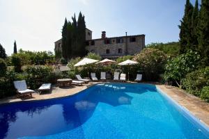 a pool with chairs and umbrellas in front of a house at Nittardi in Castellina in Chianti