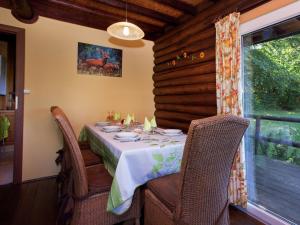 a dining room with a table and chairs and a window at Open wooden chalet built against a hill in Francorchamps