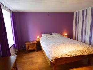 1 dormitorio con 1 cama con paredes moradas y 2 lámparas en Inviting Holiday Home in Beauraing, en Honnay