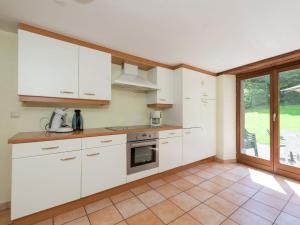 a kitchen with white cabinets and a large window at Quaint Cottage In Jevign with Terrace in Lierneux