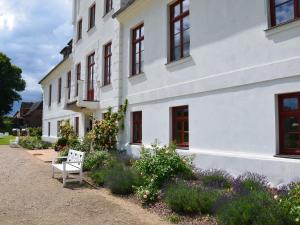 a white building with a bench in front of it at Wohnung in Satow mit Garten in Gerdshagen