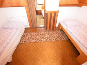 two beds in a small room with wood floors at small holiday home at the edge of the forest in Malá Skála