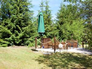 a green umbrella sitting next to two wooden benches at Ferienhaus in Gegensee am Naturpark in Ahlbeck
