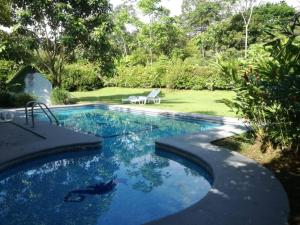 a swimming pool in a yard with a bench next to it at Casona Rústica & Bungalow in Fortuna