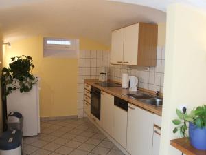 una pequeña cocina con armarios blancos y fregadero en Comfy Apartment in Wei ig with Garden, en Weißig