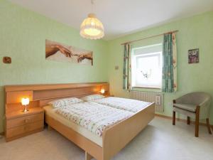 a bedroom with a bed and a chair and a window at Apartment near the Nurburgring with terrace in Hillesheim