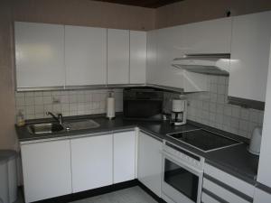 a kitchen with white cabinets and a sink at Apartment near the Nurburgring with terrace in Hillesheim