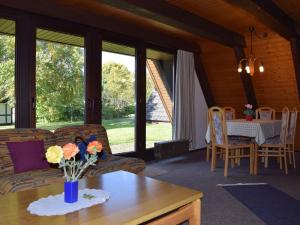 Detached, nice bungalow on Katzenbuckel mountain في Strümpfelbrunn: غرفة معيشة مع أريكة وطاولة مع زهور