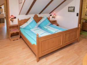 uma cama de madeira com almofadas azuis num quarto em Apartment in G tenbach with nearby forest em Furtwangen