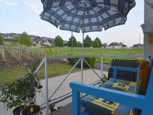 a blue chair under an umbrella on a porch at Apartment on the Moselle in Neumagen Dhron in Neumagen-Dhron