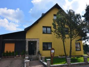 Una casa amarilla con un árbol delante. en Cosy apartment in Frauenwald near forest, en Frauenwald