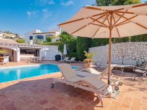 un patio con sombrilla, sillas y piscina en Belvilla by OYO Casa Gloria, en Benissa