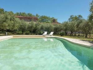 uma piscina de água com duas cadeiras num quintal em Spacious 6 person villa with pool em Autignac