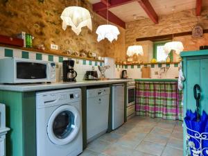 een keuken met een wasmachine en een magnetron bij Cosy holiday home with terrace near Quimperl in Coatviller