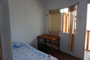a bedroom with a bed and a table and a window at Hostel Paqaryi in Zorritos