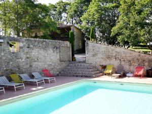a swimming pool with colorful chairs and a stone wall at Cozy House in Lot with Pool and Terrace in Saint-Caprais-de-Lerm