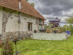 a stone house with a table and an umbrella at Cottage in Saint Clair sur l Elle in Saint-Clair-sur-lʼElle