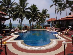 una piscina en un complejo con palmeras en el fondo en Samsara Harmony Beach Resort, en Varkala