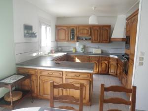 uma cozinha com armários de madeira e um balcão preto em Holiday home in Denneville near the beach em Denneville
