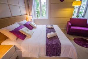 um quarto com uma cama grande e uma cadeira roxa em Peninsula Luxury Rooms em Zadar