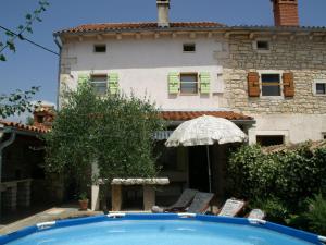 een zwembad met stoelen en een parasol voor een gebouw bij Traditional villa with private pool in Peresiji