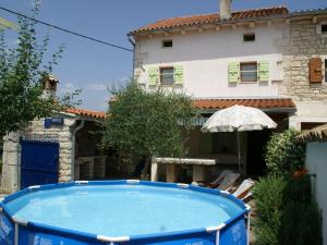 een zwembad voor een huis met een parasol bij Traditional villa with private pool in Peresiji