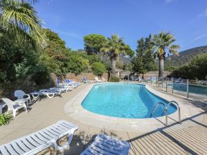 ボルム・レ・ミモザにあるAmazing holiday home in Bormes les Mimosas with poolのヤシの木が茂るスイミングプール(ラウンジチェア付)