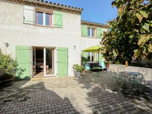 a house with green doors and a patio at Amazing holiday home in Bormes les Mimosas with pool in Bormes-les-Mimosas
