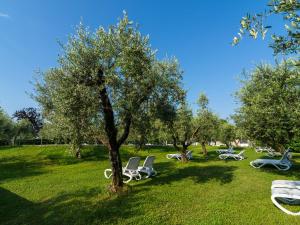 eine Gruppe von Stühlen, die im Gras in einem Park sitzen in der Unterkunft Apartment on Lake Garda in Manerba with Pool in Montinelle