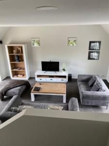 Home By Hagley Park في كرايستشيرش: غرفة معيشة مع كنبتين وتلفزيون بشاشة مسطحة