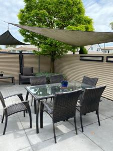 tavolo e sedie con tavolo in vetro e ombrellone di Home By Hagley Park a Christchurch