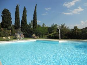 a large blue swimming pool in a yard with trees at Belvilla by OYO Villa Rapolano in Rapolano Terme