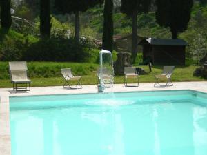 a swimming pool with two chairs and a fountain at Belvilla by OYO Villa Rapolano in Rapolano Terme