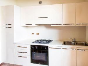 una cucina con armadi bianchi, piano cottura e lavandino di Belvilla by OYO Casa Mon ga a Moniga