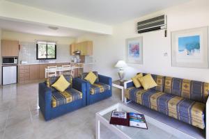 a living room with two blue couches and a kitchen at Club Aphrodite in Erimi